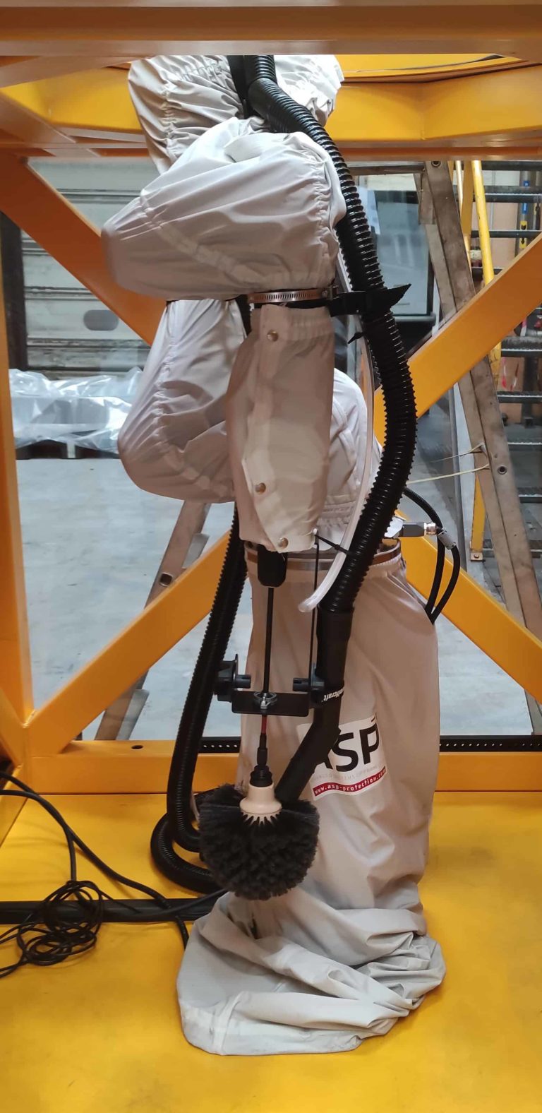 Robot sur colonne élévatrice dans une cage de protection avec une brosse de nettoyage